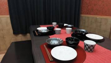 Una mesa dispuesta con varios cuencos y platos, un par de palillos y un mantel individual rojo.