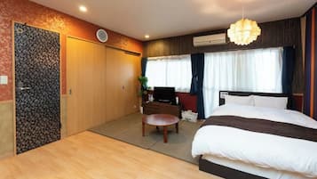 Habitación de hotel con cama, escritorio, silla, televisor y ventana con cortinas.