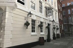 A building with white walls, multiple windows, hanging flower baskets, and a sign above the entrance. - Eldon Chambers Pod 5 by City Living London (London)