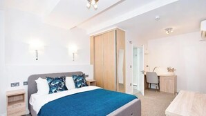 Une chambre à coucher moderne avec un lit, des tables de chevet, un bureau et une armoire.