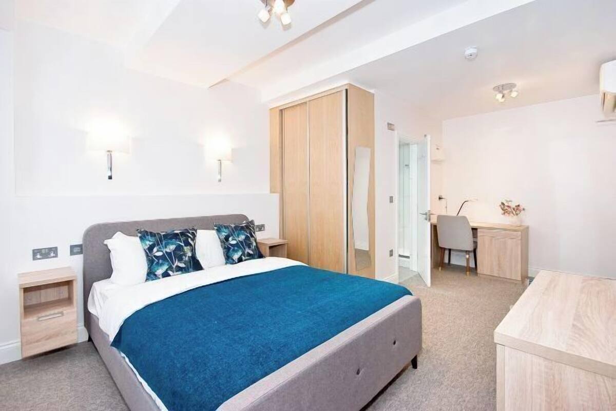 Une chambre à coucher moderne avec un lit, des tables de chevet, un bureau et une armoire.