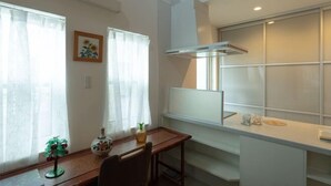 Eine moderne Küche mit weißer Arbeitsplatte, einem eingebauten Ofen und einem Fenster mit Milchglas.