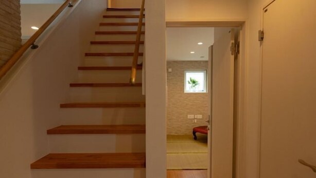 Eine Holztreppe führt zu einem Raum mit Fenster und Tür.