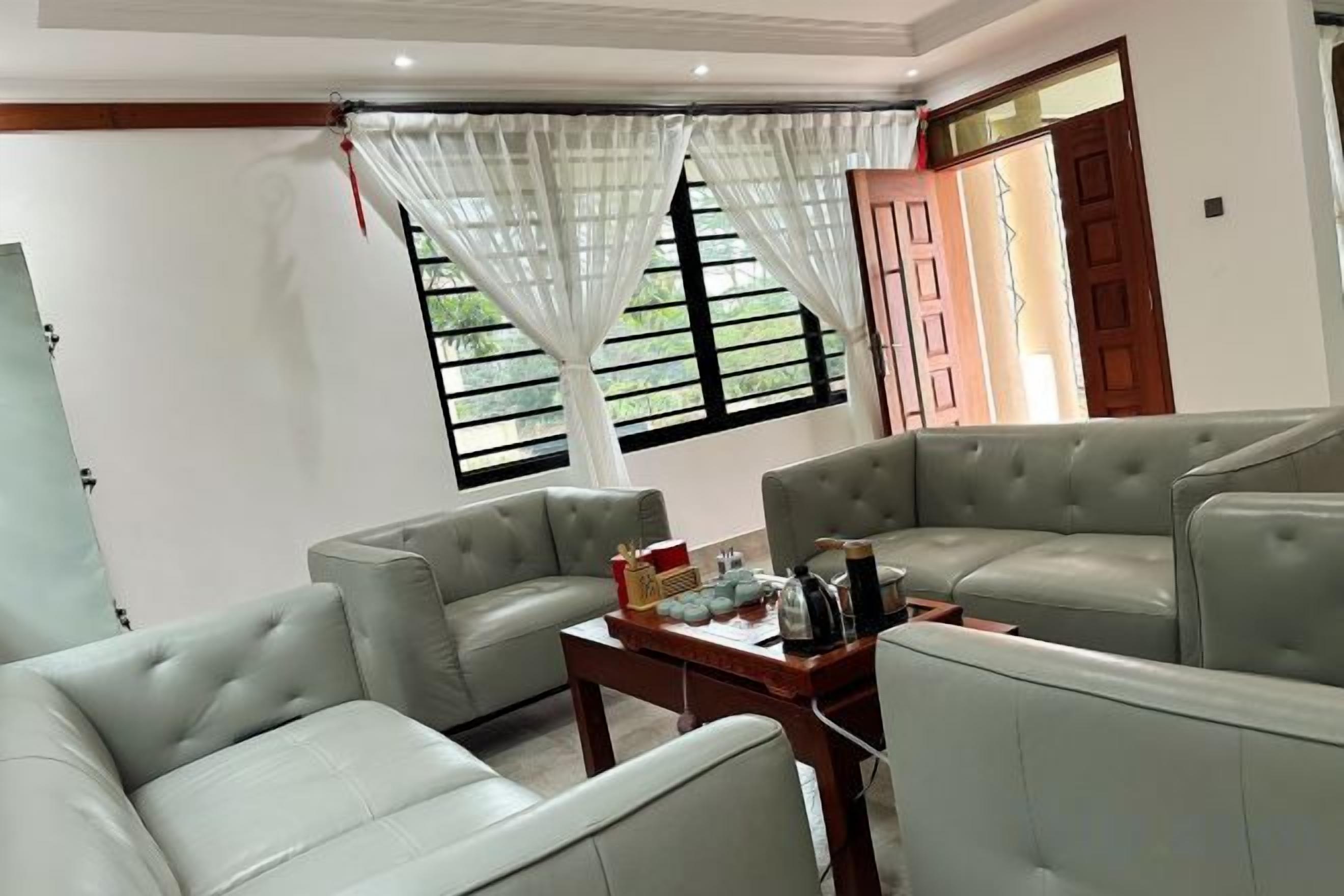 A living room with two grey sofas, a coffee table with items, and a window with curtains.