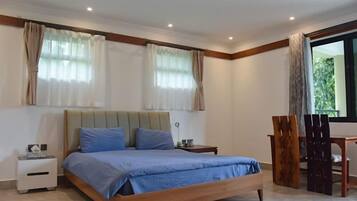 A bedroom with a bed, bedside tables, a chair, and a window with curtains.