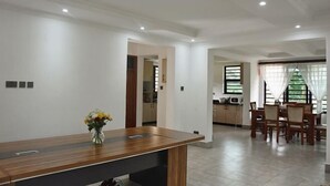 Un vaste espace de vie comprenant une table basse en bois, une table à manger avec des chaises, et une cuisine située à l’arrière-plan.