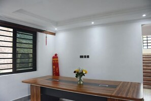 Een vergaderruimte met een houten tafel, een vaas met bloemen en een rode decoratie aan de muur.