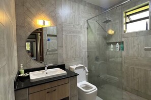 Een moderne badkamer met douche, toilet en wastafel.