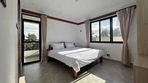 Une chambre dotée d’un grand lit, de portes-fenêtres coulissantes donnant sur un balcon et offrant une vue sur l’extérieur.