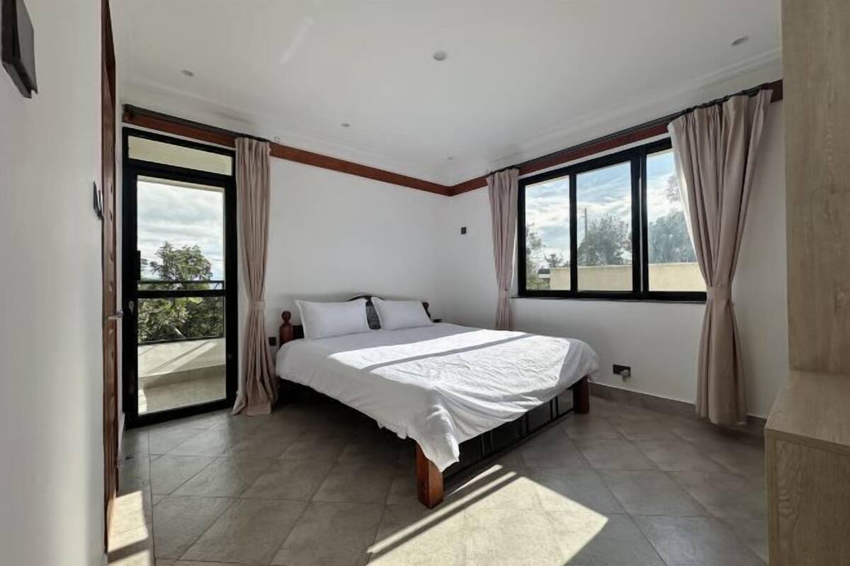 Un dormitorio con una cama grande, puertas corredizas de vidrio a un balcón y vistas al exterior.