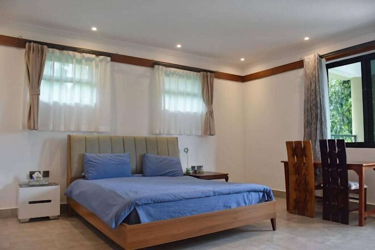 Un dormitorio con una cama de madera, una mesita de noche, un escritorio y una ventana con cortinas.
