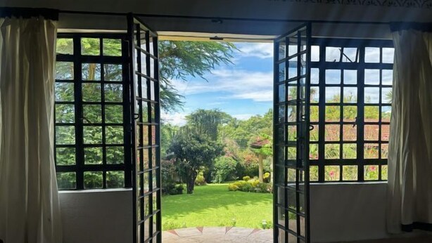 Une pièce dotée d’une grande fenêtre ouverte, offrant une vue imprenable sur un jardin luxuriant.