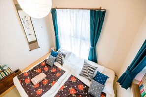 A room with a bed, a bedside table, a window with curtains, and a wall-mounted artwork. - Tokyo Dome City Amusement Park Homestay (Tokyo)
