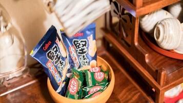 A wooden bowl containing packaged snacks and a ceramic plate with a white object.