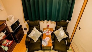 A small living area with a sofa, a coffee table, and a TV. - Tokyo Dome City Amusement Park Homestay (Tokyo)