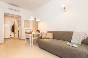 A modern living room with a sofa, a dining table, and pendant lights. - Colosseum Holidays - Marco Aurelio (Rome)