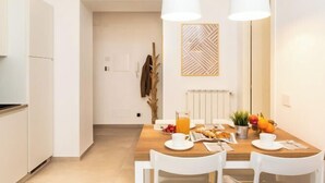 A modern kitchen with white cabinets, a wooden dining table with white chairs, and pendant lights.