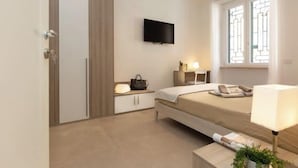 A modern bedroom with a bed, bedside table, lamp, TV, and a window with a view.