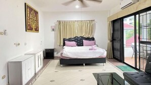 A bedroom with a bed, a ceiling fan, a radiator, a window with curtains, and a view of the outside. - royal park 217 (Pattaya)