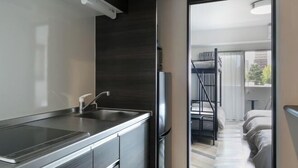 Eine moderne Küche mit einer Edelstahl-Spüle, dunklen Schränken und einem Kühlschrank.