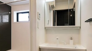 Ein modernes Badezimmer mit Badewanne, Waschbecken und einem Spiegel darüber sowie einem Fenster mit Tageslicht.