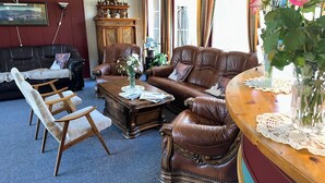A traditional living room with leather furniture, a wooden coffee table, and a vintage clock. - Bjorliheimen Fjellhotell-Hotellrom (Lesja)