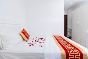 A hotel room with a bed, a red and gold decorative runner, and a wardrobe. - Phu Gia Hotel 99-101 Him Lam (Ho Chi Minh City)