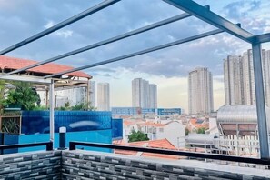 A cityscape view from a balcony with a metal framework, high-rise buildings, and a clear sky. - Phu Gia Hotel 99-101 Him Lam (Ho Chi Minh City)