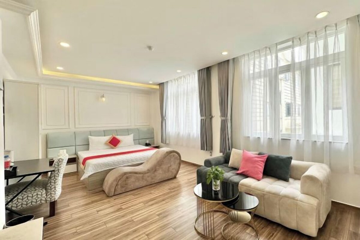 A modern hotel room with a bed, sofa, and a small round table.