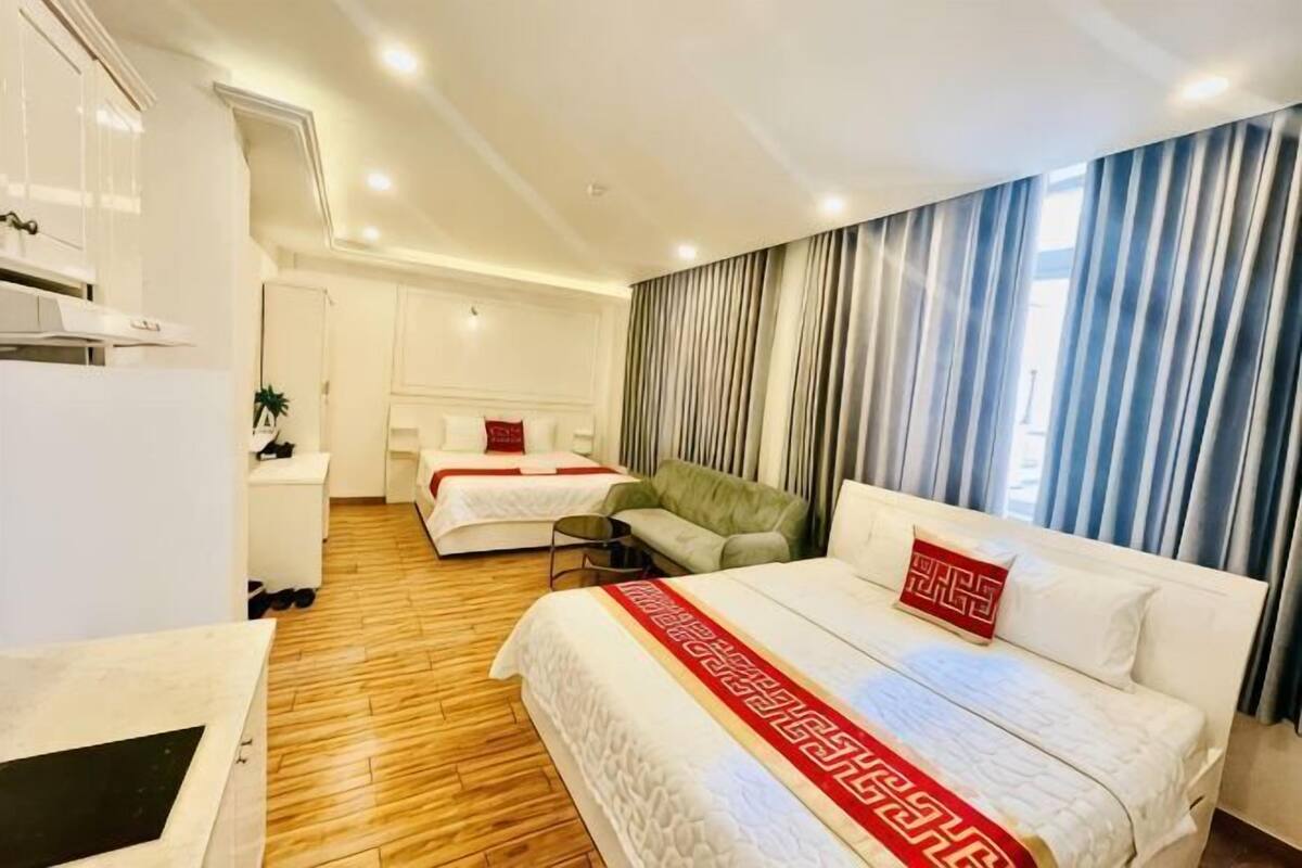 Ein Hotelzimmer mit einem großen Bett, einem kleineren Bett, einem Schlafsofa, einem Schreibtisch und einer Küchenzeile.