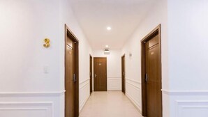 A hallway with three wooden doors, white walls, and a tiled floor. - Phu Gia Hotel 99-101 Him Lam (Ho Chi Minh City)