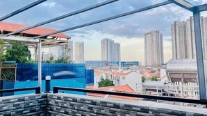 A cityscape view from a balcony with a metal framework, high-rise buildings, and a blue wall. - Phu Gia Hotel 99-101 Him Lam (Ho Chi Minh City)