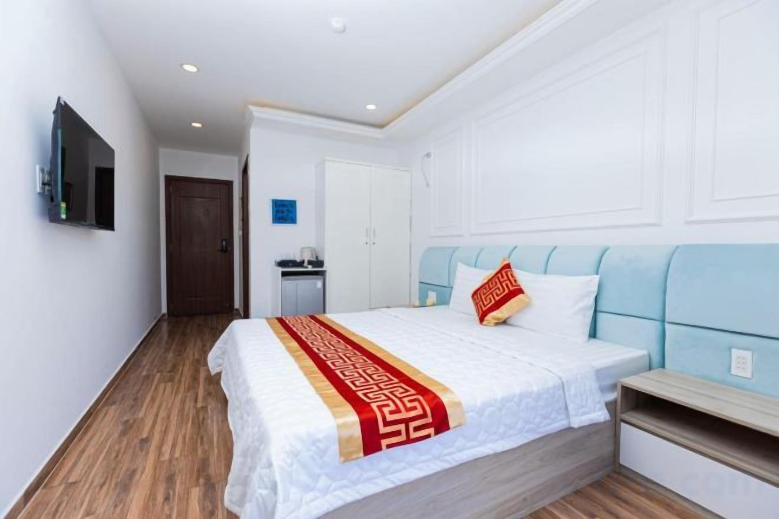 A hotel room with a bed, bedside table, and a TV mounted on the wall.