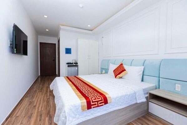 Une chambre d’hôtel équipée d’un lit, d’une table de chevet et d’un téléviseur fixé au mur.