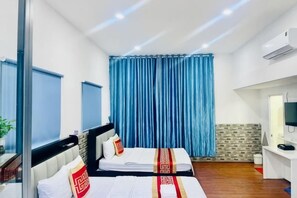 Une chambre d’hôtel avec deux lits, un bureau, une télévision et une fenêtre avec des rideaux.