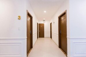 Un couloir avec deux portes de chaque côté, menant à une pièce au bout.