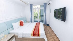 A hotel room with a bed, a nightstand, a window with curtains, and a wall-mounted TV. - Phu Gia Hotel 99-101 Him Lam (Ho Chi Minh City)