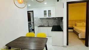 A compact living space with a kitchen, dining area, and a bed. - Phu Gia Hotel 99-101 Him Lam (Ho Chi Minh City)