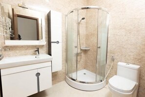 Une salle de bain avec une douche à parois de verre, des toilettes et un lavabo avec un miroir au-dessus.