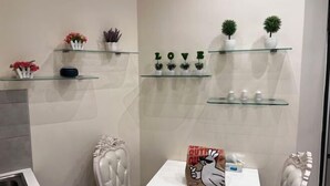 Een badkamer met een witte wastafel, een glazen plank met planten en een bord waarop 'LOVE' staat.