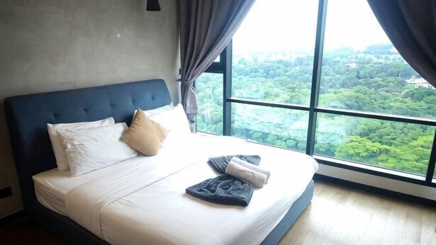 A bed with white linens, a blue headboard, and a view of greenery through large windows. - 8Pax/Green View next to KL118 ChinaTown & Train (Kuala Lumpur)