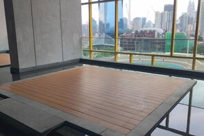 A room with a wooden floor, large windows, and a view of a cityscape. - 8Pax/Green View next to KL118 ChinaTown & Train (Kuala Lumpur)