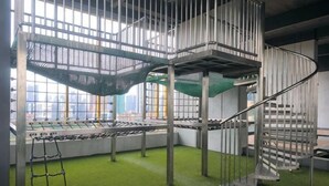 A multi-level indoor play area with climbing structures, a ladder, and a green artificial turf floor. - 8Pax/Green View next to KL118 ChinaTown & Train (Kuala Lumpur)