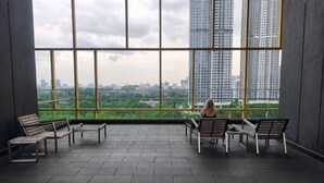 A spacious indoor area with large windows, multiple benches, and a view of high-rise buildings. - 8Pax/Green View next to KL118 ChinaTown & Train (Kuala Lumpur)