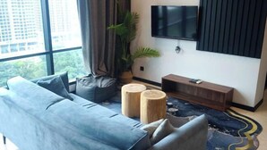 A modern living room with a sofa, a TV mounted on the wall, a plant, and a wooden console table. - 8Pax/Green View next to KL118 ChinaTown & Train (Kuala Lumpur)