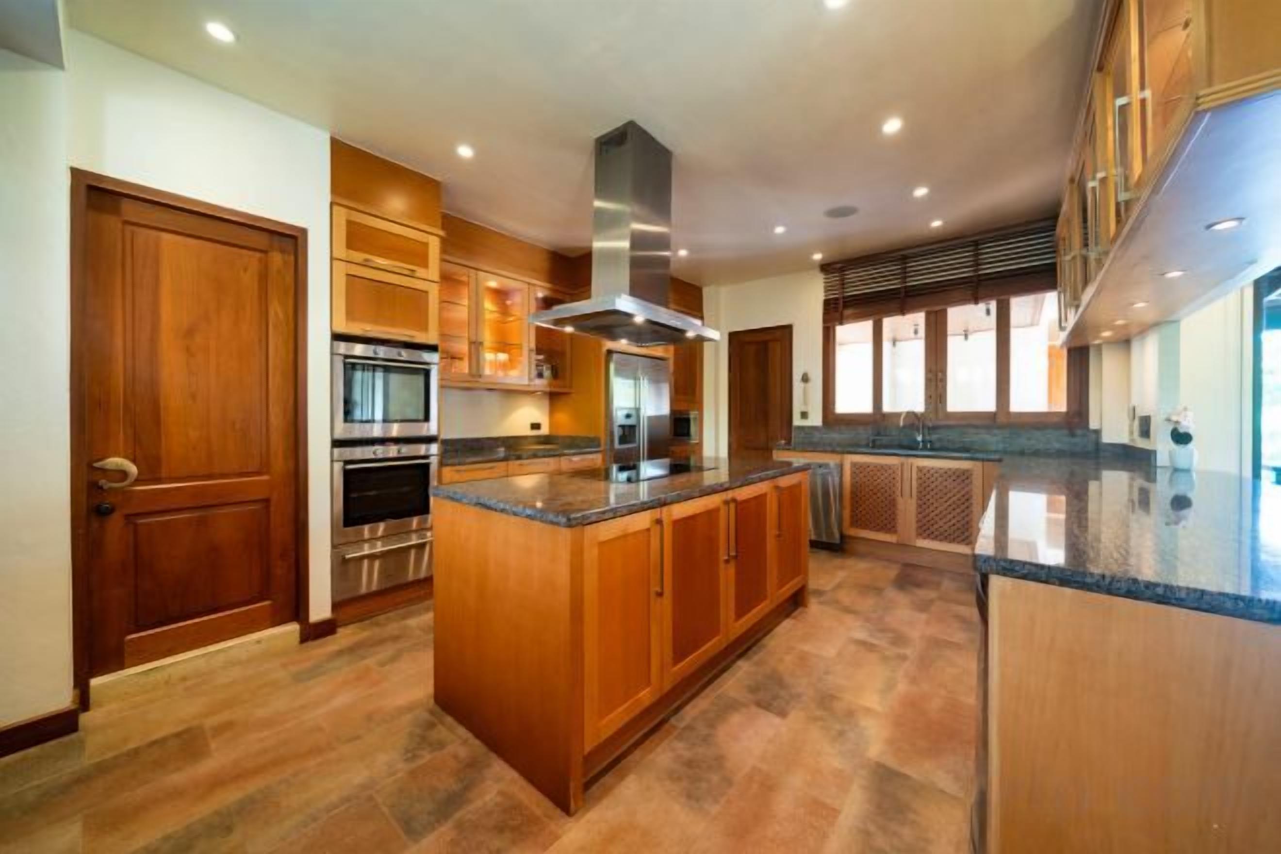 Une cuisine spacieuse dotée de meubles en bois, d’appareils électroménagers en acier inoxydable et d’un grand îlot central.