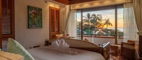 Een hotelkamer met een bed, uitzicht op palmbomen en een balkon.