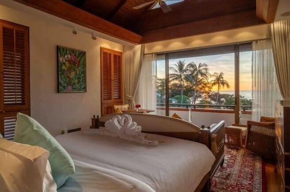 A hotel room with a bed, a view of palm trees, and a balcony. - Boutique 5 Bedroom Seaview Pool Villa Kata Beach Phuket Warm Plus (Phuket)
