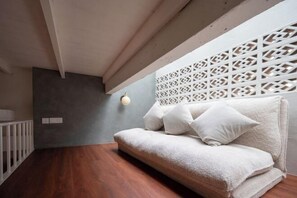 A modern room with a wooden floor, a white sofa with cushions, a white partition with a geometric pattern, and a wall-mounted light fixture. - Lumut Heritage - a walk to Armenian St Art & Cafes (George Town)