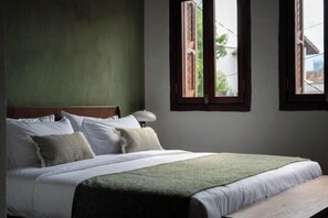 A bed with white linens, a green throw, and a wooden headboard. There are two windows with brown frames, one of which is open. - Lumut Heritage - a walk to Armenian St Art & Cafes (George Town)